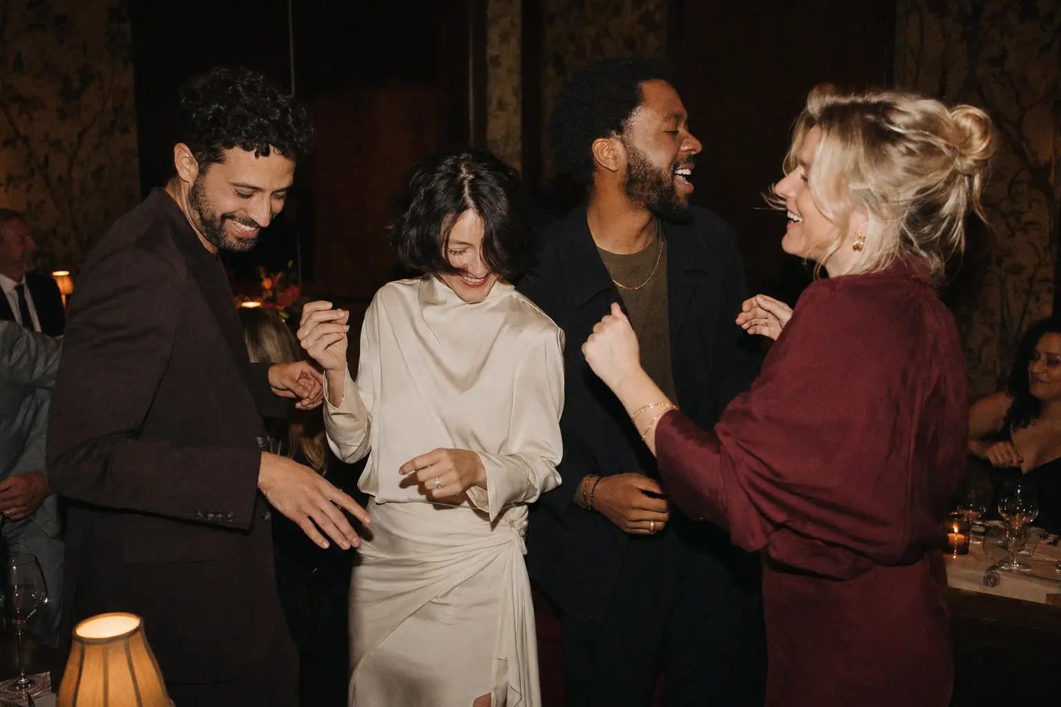 Four adult friends dancing after dinner
