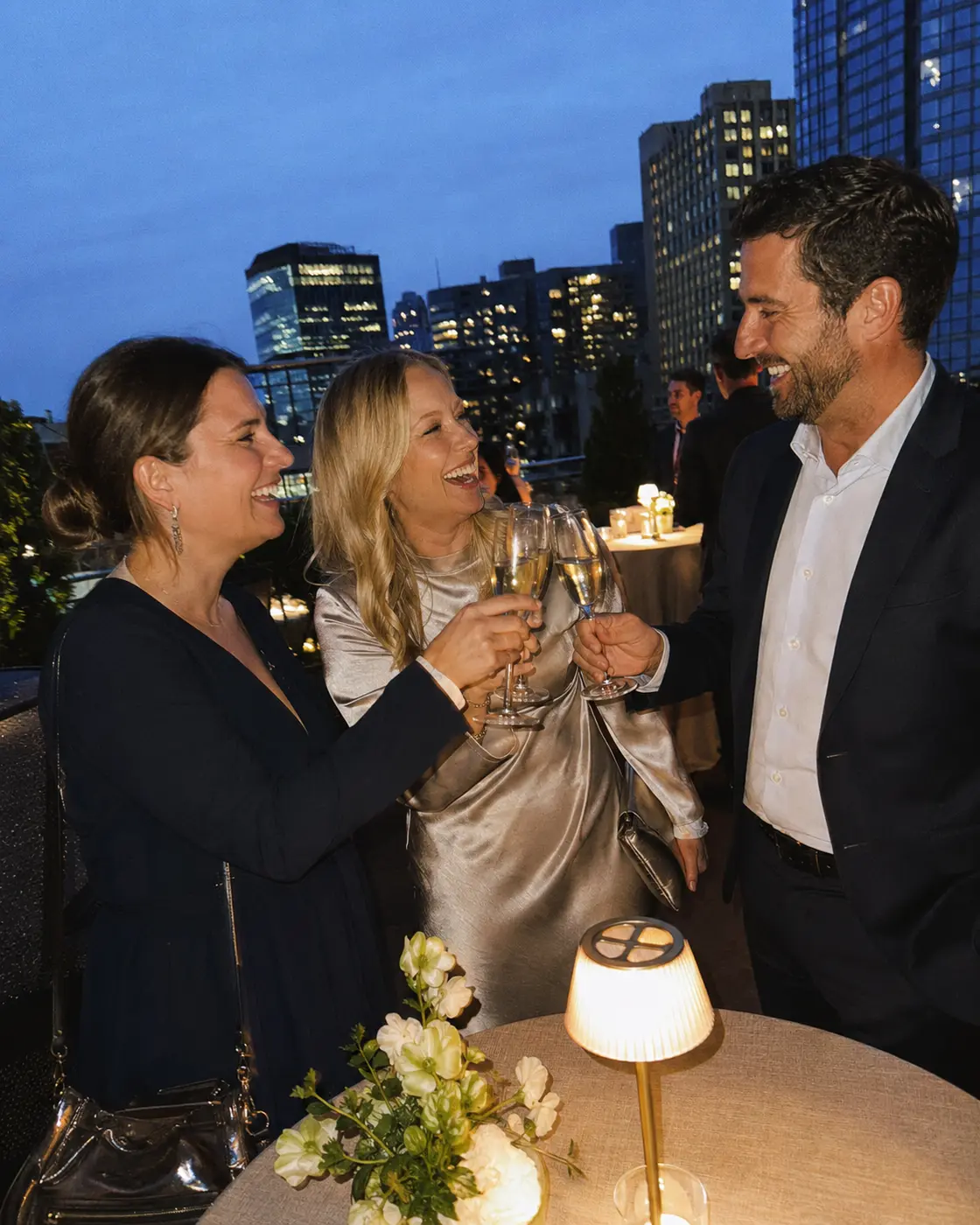 Three adult friends making a toast on a city rooftop